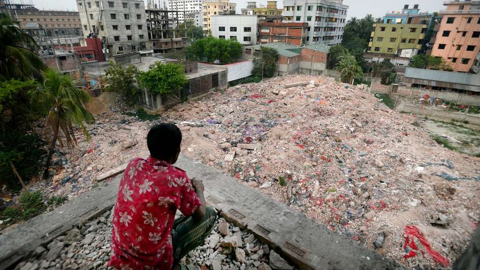 Ein Mann sitzt vor den Trümmern der Textilfabrik Rana Plaza in Bangladesch.