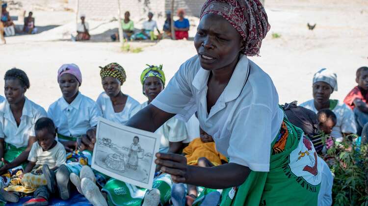 Eine Frau hält ein Plakat in der Hand und erklärt.