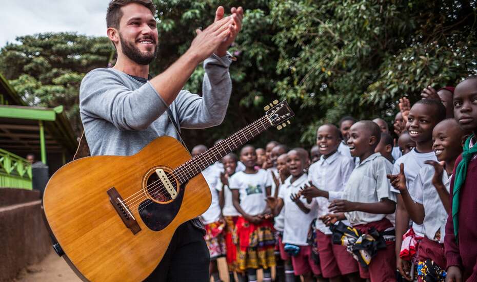 Sänger und Songwriter Robert Redweik mit Gitarre bei seinem Besuch des "Skill up!"-Projekts der Welthungerhilfe in Kenia.
