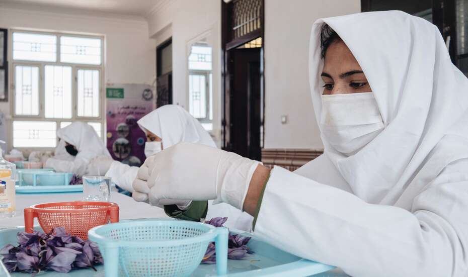 Eine Frau mit Mundschutz sitz an einem Tisch.
