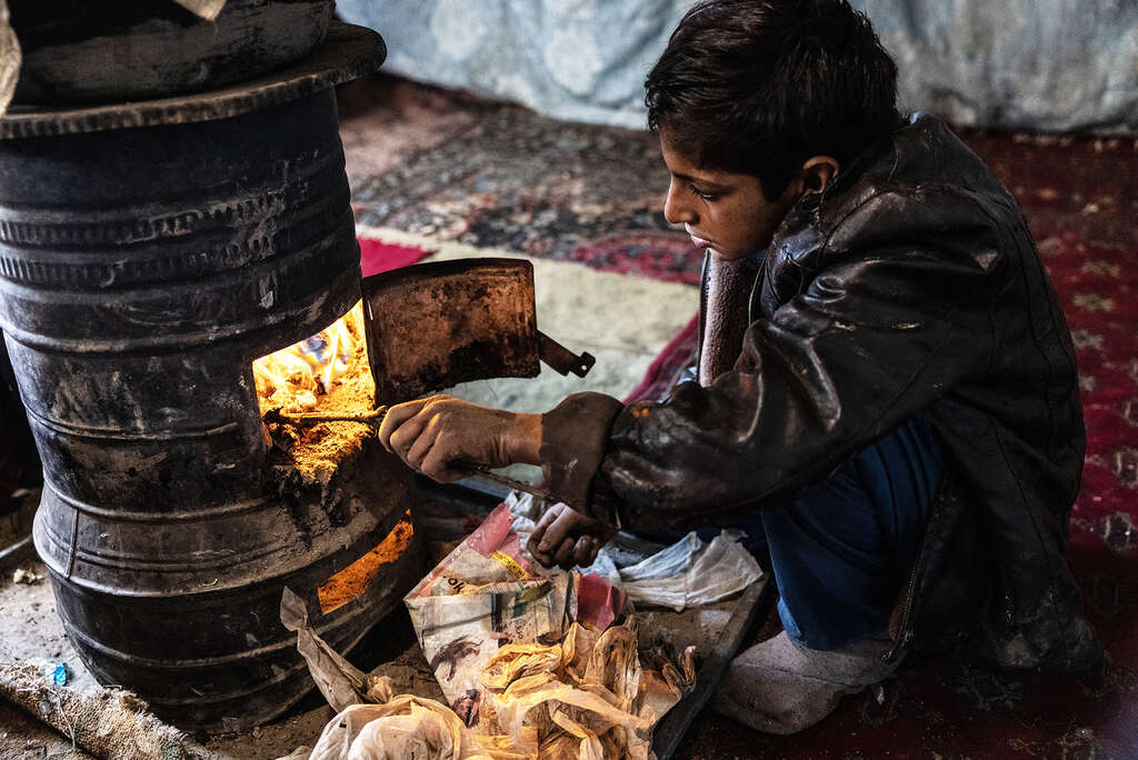 Der 10-jährige Noor aus Kabul heizt den Ofen an, den die Familie zum Kochen verwendet und gleichzeitig zum Heizen des Hauses. Holz oder Kohle können sie sich nicht leisten. 