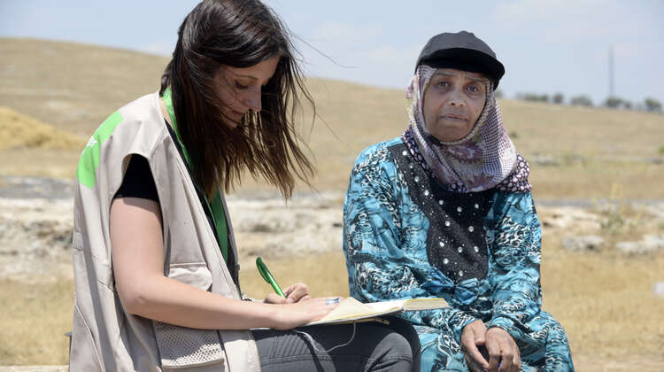 Zwie Frauen sitzen nebeneinander, eine Frau schreibt etwas auf.