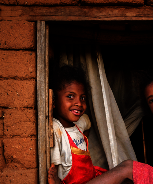 Zwei Mädchen sitzen auf einem Fenster und lachen.