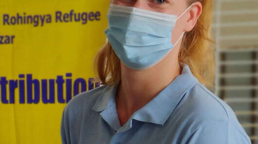 Eine Frau mit Mundschutz blickt in die Kamera.