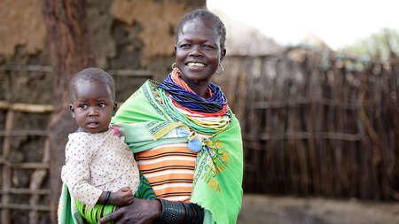 Eine lachende Frau mit einem Baby auf dem Arm.