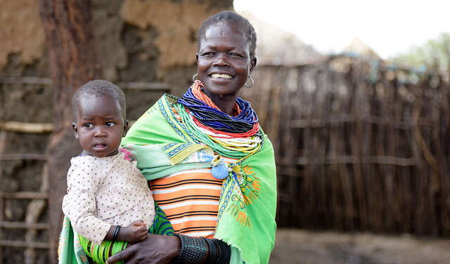 Eine lachende Frau mit einem Baby auf dem Arm.