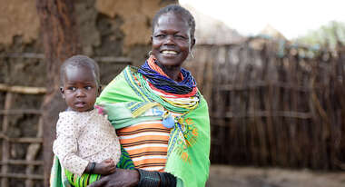 Eine lachende Frau mit einem Baby auf dem Arm.