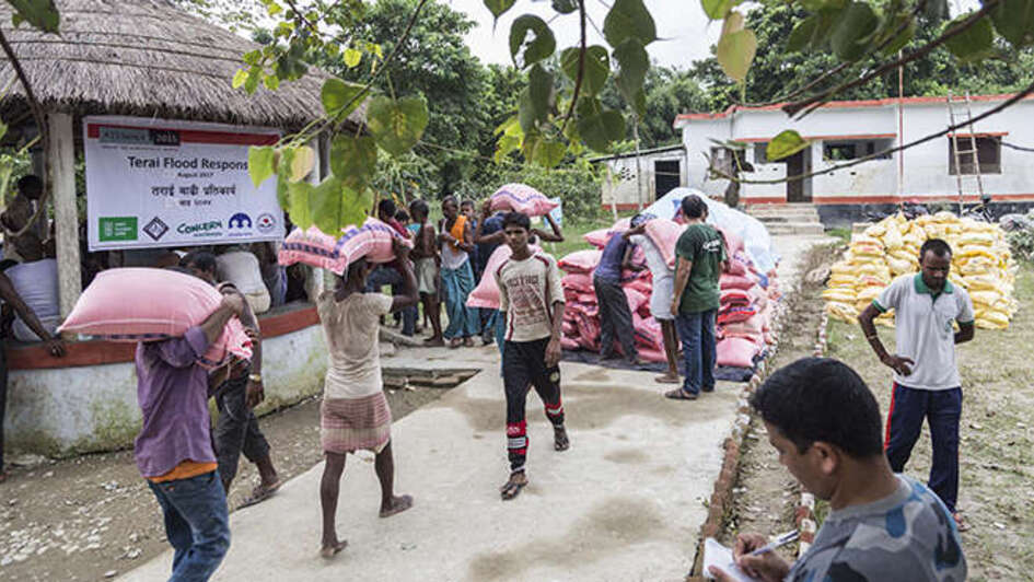 Menschen tragen Nahrugsmittel-Säcke