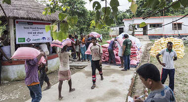 Menschen tragen Nahrugsmittel-Säcke