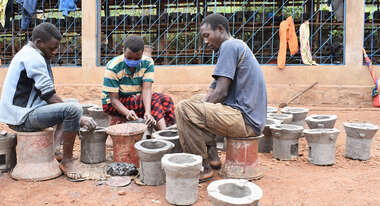 Drei junge Menschen sitzen sich gegenüber und töpfern Öfen, Burundi 2021 