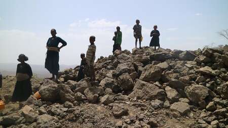 Menschen stehen auf einem Berg ausgetrockneter Erde.