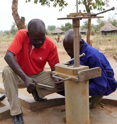 Zwei Männer arbeiten an einem Brunnen