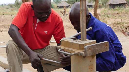 Zwei Männer arbeiten an einem Brunnen
