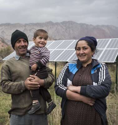 Eine Familie vor ihrer Solaranlage in Tadschikistan.