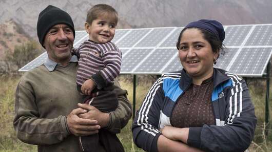 Eine Familie vor ihrer Solaranlage in Tadschikistan.