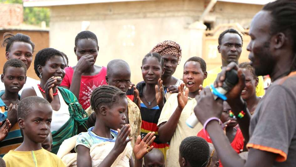 Junge Dorfbewohner applaudieren dem Musiker.