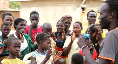 Junge Dorfbewohner applaudieren dem Musiker.