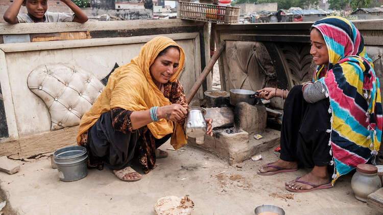 Zwei Frauen sitzen auf dem Boden und kochen.