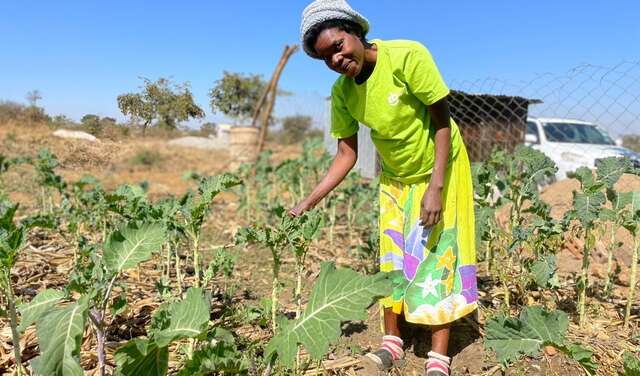 Eine Frau steht in einem Gemüsebeet.