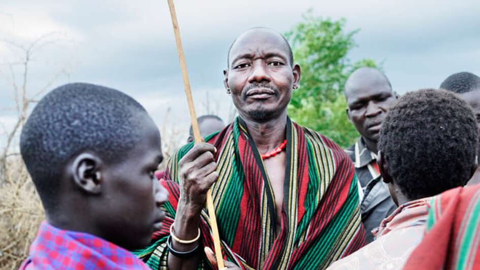 Mehrere Personen sind abgebildet, ein Mann schaut direkt in die Kamera