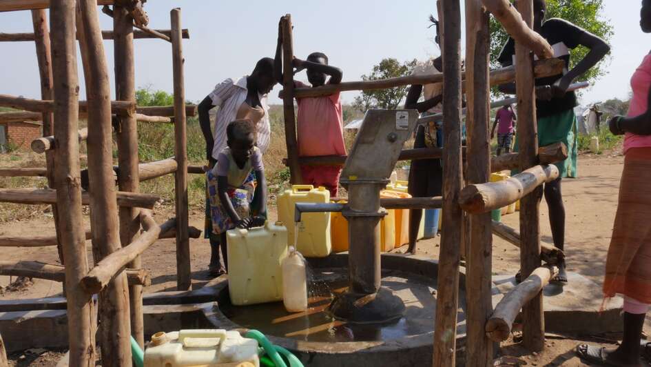 Menschen füllen an einem Brunnen Wasser ab