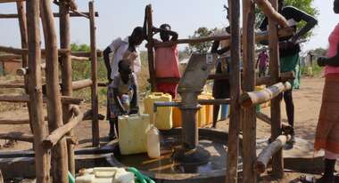 Menschen füllen an einem Brunnen Wasser ab