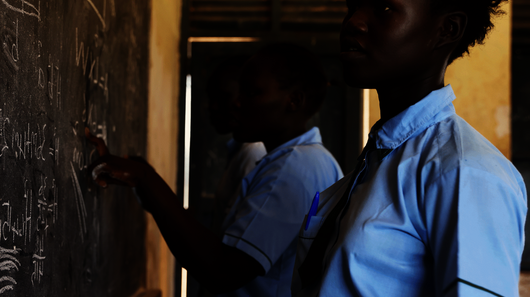 Bild aus einem Projekt im Südsudan mit Schulspeisungen, ein Mädchen steht an einer Schultafel.