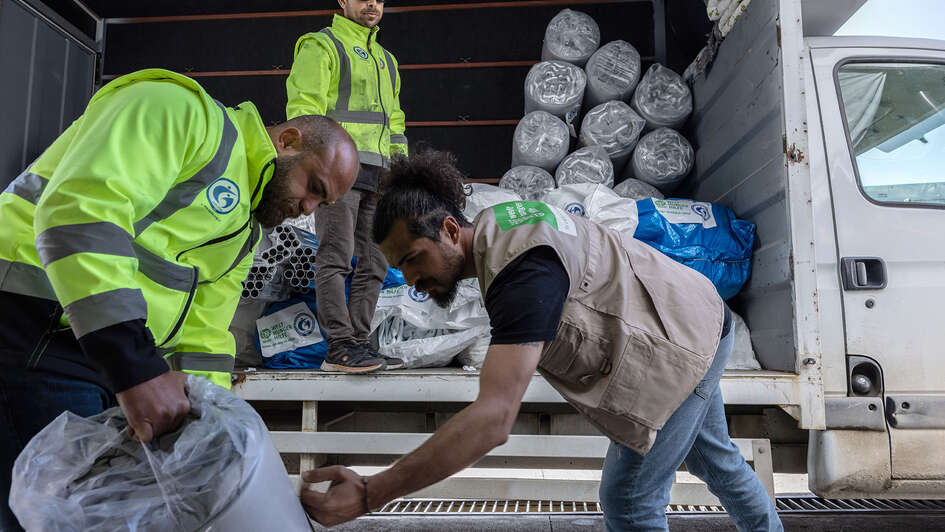 Drei Männer beladen einen LKW.