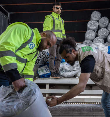 Drei Männer beladen einen LKW.