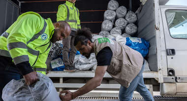 Drei Männer beladen einen LKW.