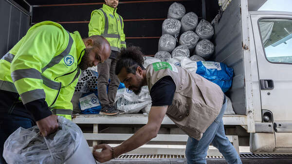 Drei Männer beladen einen LKW.