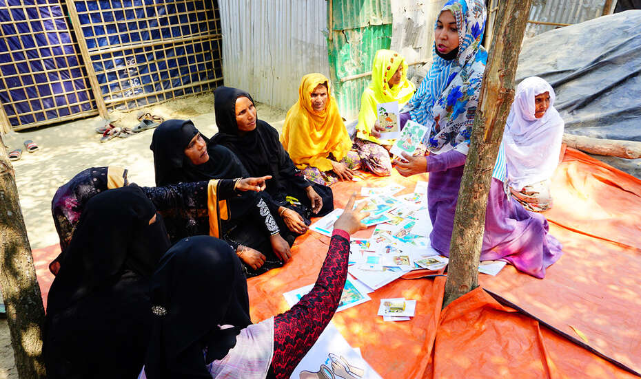 Im Halbkreis sitzende Frauen, eine Frau in der Mitte.