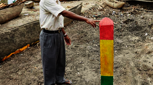 Ein Mann zeigt einen dreifarbigen Balken, der im Sand befestigt ist.