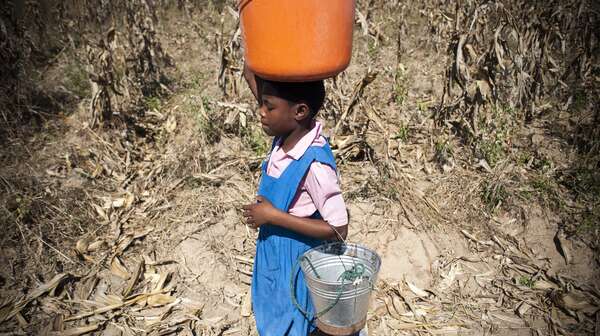Mädchen trägt Eimer auf dem Kopf