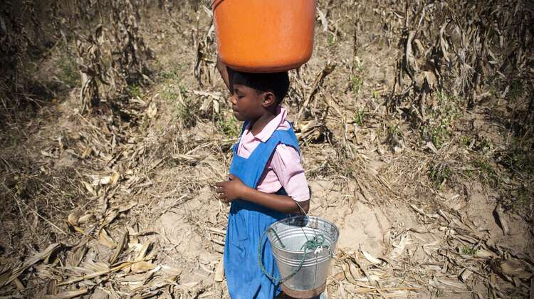 Chimwemwe trägt einen Eimer Wasser