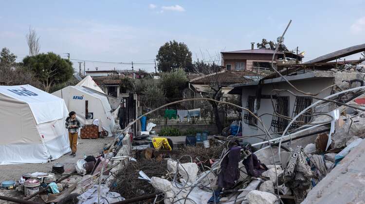 Ein altes und durchs Erdbeben zerstörtes Haus steht neben neu aufgebauten Zelten.