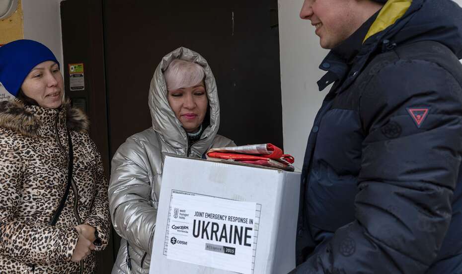 Eine Mutter und ihre erwachsene Tochter bekommen ein Hilfspaket mit Lebensmitteln überreicht