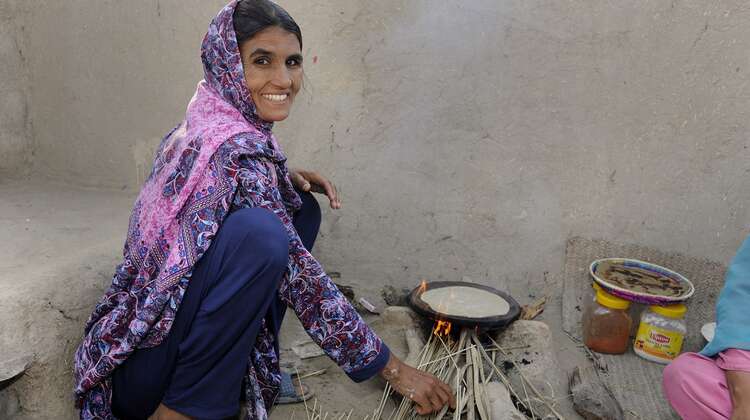 Eine Frau kocht in Hocke.