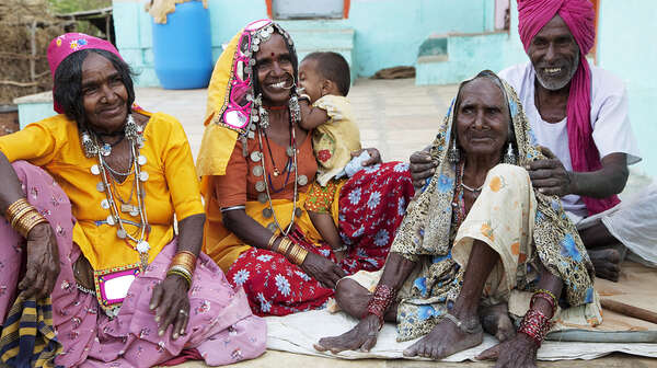 ältere Frauen in bunten Kleidern sitzen auf dem Boden