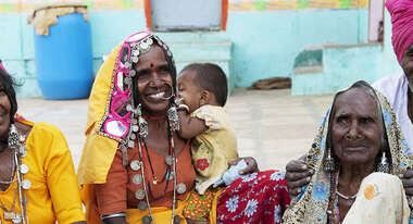 ältere Frauen in bunten Kleidern sitzen auf dem Boden