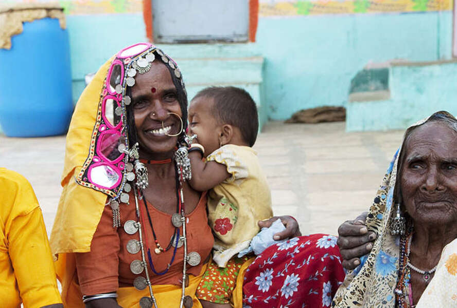 ältere Frauen in bunten Kleidern sitzen auf dem Boden
