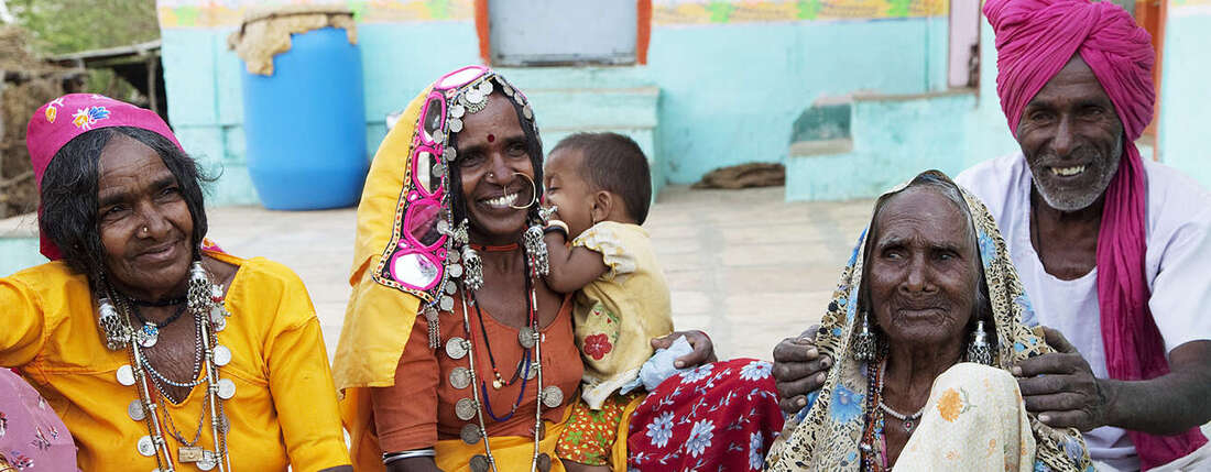 ältere Frauen in bunten Kleidern sitzen auf dem Boden