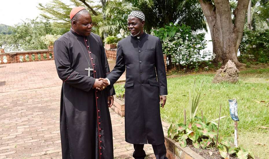 Zwei schwarz gekleidete Männer geben sich die Hand.