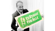 Schauspieler Till Demtrøder hält ein Schild mit dem Welthungerhilfe-Hashtag #EsReichtFürAlle.