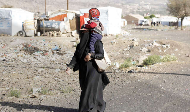 Nothilfe in Jemen. Eine Mutter trägt ihr Kind durch das Dharawan Flüchtlingscamp in Sanaa.