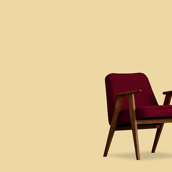 Ein dunkelroter und ein grüner Sessel sowie ein Mikrofon vor gelbem Hintergrund. 