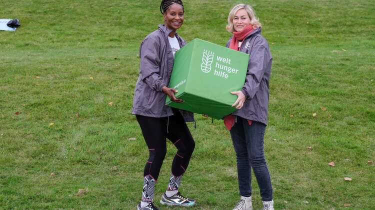 Zwei Frauen halten einen grünen Würfel mit Welthungerhilfe-Logo.