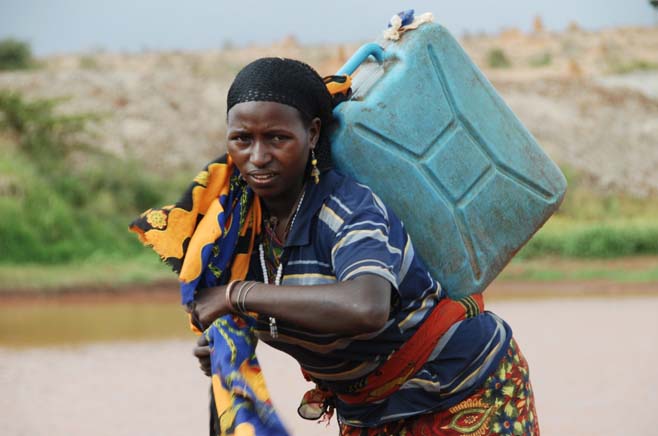Eine Frau schleppt einen Wasserkanister.